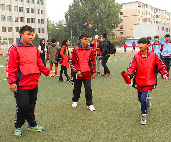 学生们在操场上快乐地玩耍心理健康游戏,锻炼自身协调能力和团队