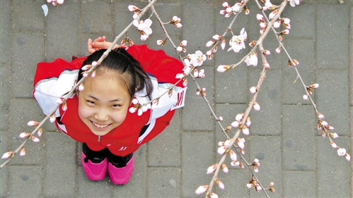 4月7日,内蒙古农业大学附属中学的一名学生正在欣赏校园内的桃花.