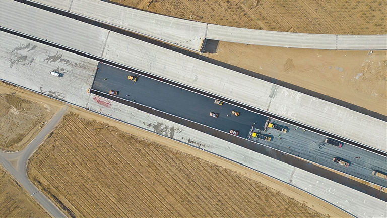 近日,工人在s43呼和浩特机场高速公路项目建设现场进行桥面沥青摊铺